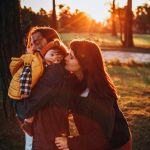 woman in brown long sleeve shirt carrying girl in white shirt